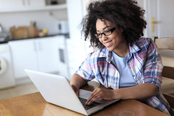 Woman with eyeglasses using laptop at home Smiling woman with eyeglasses using laptop at home. financial education stock pictures, royalty-free photos & images
