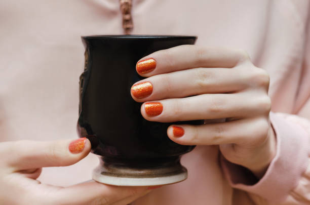 istock Female hands with orange nail design. 822570718