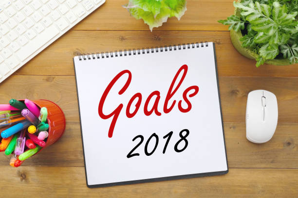 istock 2018 goals on paper note book background on office table, business and new year concept 822578270