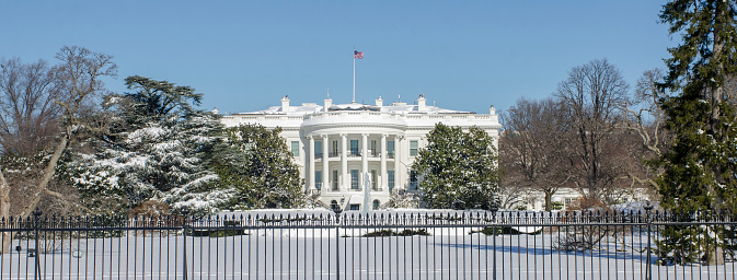 The White House and grounds are covered with snow beneath a bright blue sky, Washington, DC
