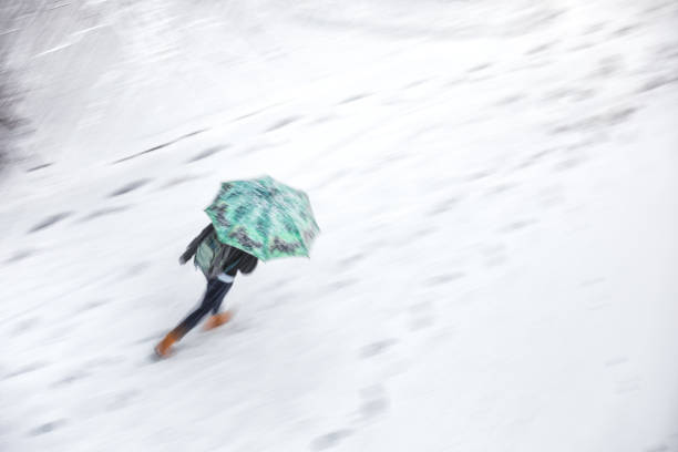 Walking With Umbrellas In Snowstorm Young man walking with umbrellas in snowstorm. Blurred motion - view from above. slippery unrecognizable person safety outdoors stock pictures, royalty-free photos & images