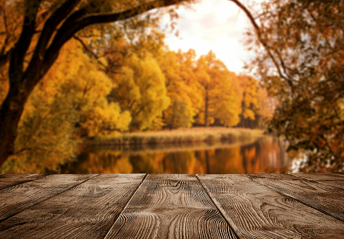 Autumn background, close up of old empty wooden table over the lake with copy space