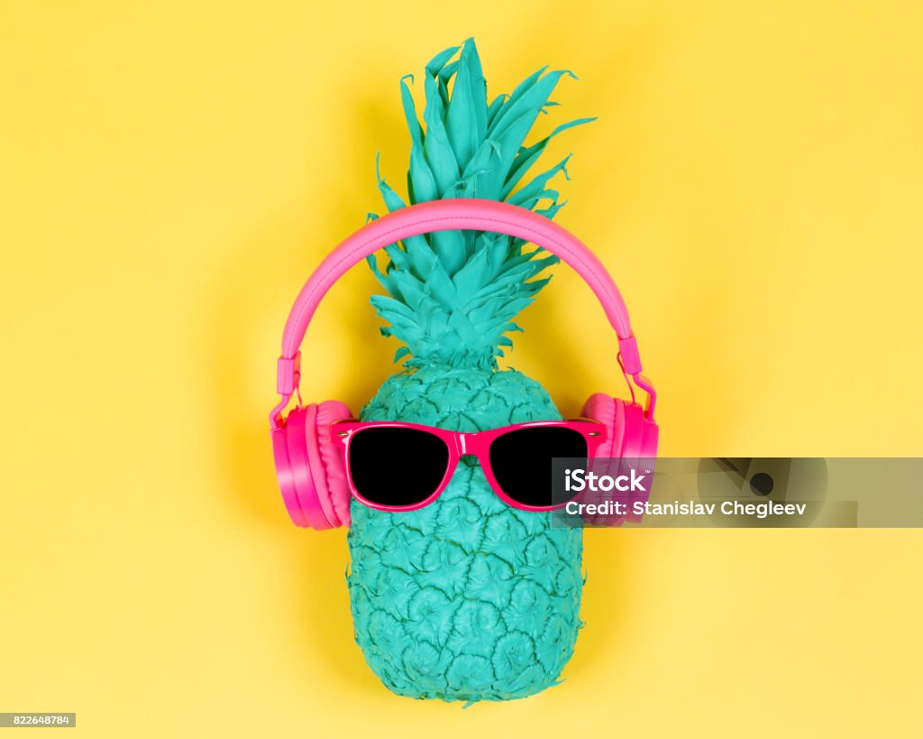 Pineapple in pink headphones Pineapple in pink headphones and glasses on a yellow background Summer Stock Photo