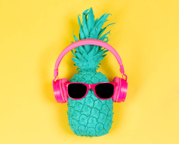 Pineapple in pink headphones Pineapple in pink headphones and glasses on a yellow background tropical music stock pictures, royalty-free photos & images