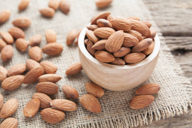 group of almonds  from wood bowl on wood background group of almonds  from wood bowl on wood background almond stock pictures, royalty-free photos & images