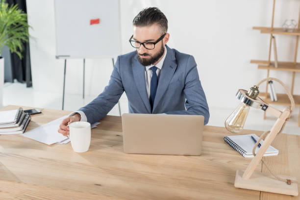 istock businessman holding coffee cup while sitting at workplace with laptop in office 822684734