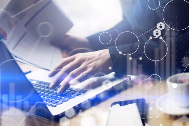 istock Concept of digital screen,virtual connection icon,diagram,graph interfaces.Businessman working at sunny office on laptop while sitting at the wooden table.Man holding paper documents in hands.Blurred. 822702072
