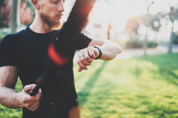 istock Workout smart lifestyle concept.Bearded muscular athlete doing great exercising  outside in summer park.Young handsome man in sportswear checking sport watch tracker.Blurred background,flares. 822706066