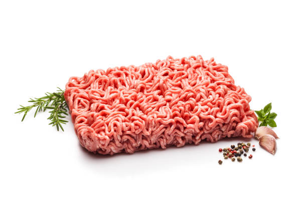 Minced meat block isolated on white background Horizontal shot of one kilogram of minced meat isolated on white background. Some cooking and seasoning ingredients like rosemary, garlic, peppercorns and oregano are around the block of minced meat. Predominant colors are red and white. DSRL studio photo taken with Canon EOS 5D Mk II and Canon EF 100mm f/2.8L Macro IS USM ground beef photos stock pictures, royalty-free photos & images