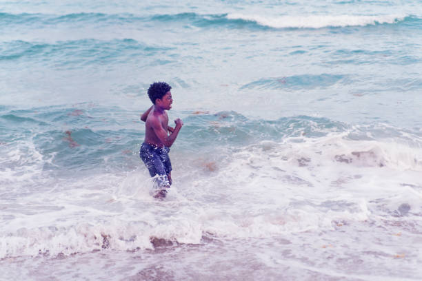 istock Young african american boy playing in the ocean. 822740148