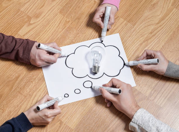 istock Thinking speech bubble balloon with light bulb. Brainstorming new ideas together for marketing plan or school project. Teamwork, synergy and education. Group of people drawing to same paper. 822796104