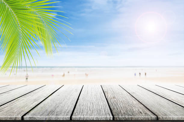 istock Empty wooden table and palm leafs with party on beach background blurred. 822806670