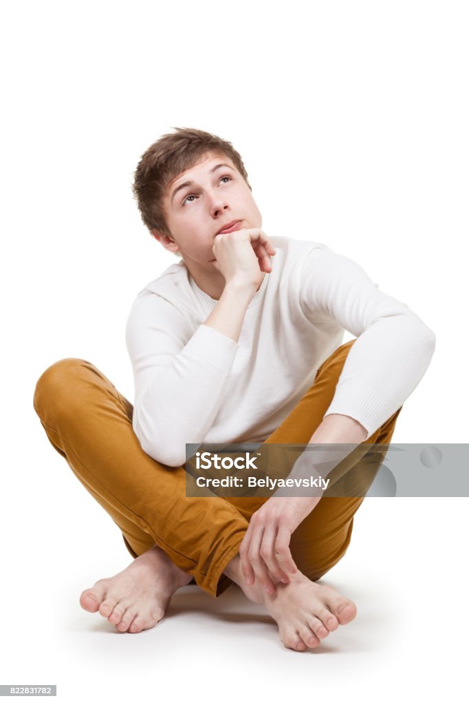Pensive Teenager On White Teenager sits in a thoughtful pose on white background Sitting Stock Photo