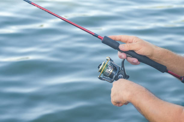 istock Fisherman's hands with spinning on the background of water 822836656