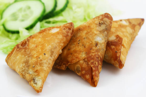 istock Three Indian samosas with green lettuce and slices of cucumber 822878654