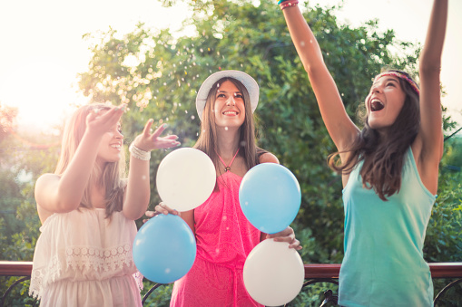 Teenager girl friends partying by throw colourful confetti from hands
