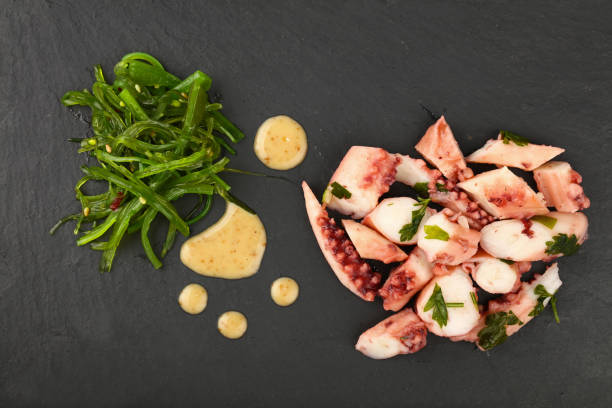 istock Octopus arm slices and seaweed salad on black 822924438