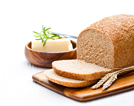 Sliced  slow-baked organic wholemeal bread with butter and rosemary and wheat ears