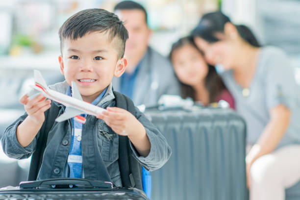 Future Pilot An Asian mother, father, son and daughter are indoors at an airport. The father is wearing a suit and the rest are wearing casual clothes. The boy is playing with toy plane while they wait to board their flight. airports canada stock pictures, royalty-free photos & images
