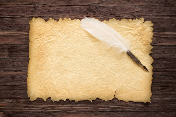 istock White feather and old paper on wood surface 822994328