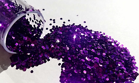 Abstract image of purple glitter spilled over a white background