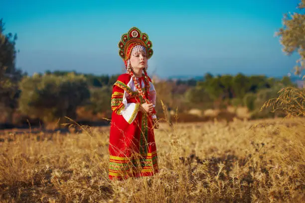 Russian beauty girl in traditional folk costume in field