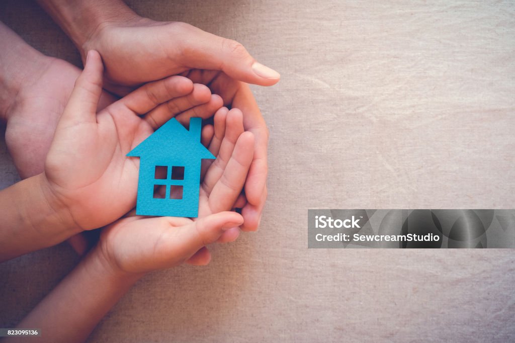 Adult and child hands holding paper house, family home and real estate concept House Stock Photo