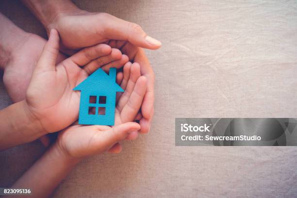 Adult And Child Hands Holding Paper House Family Home And Real Estate Concept Stock Photo - Download Image Now