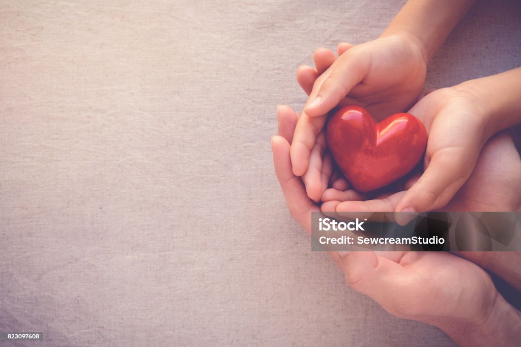 mani per adulti e bambini che zoppiano cuore rosso, amore per la salute e concetto di famiglia - Foto stock royalty-free di Beneficenza