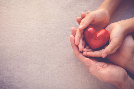 adult and child hands holiding red heart, health care love and family concept