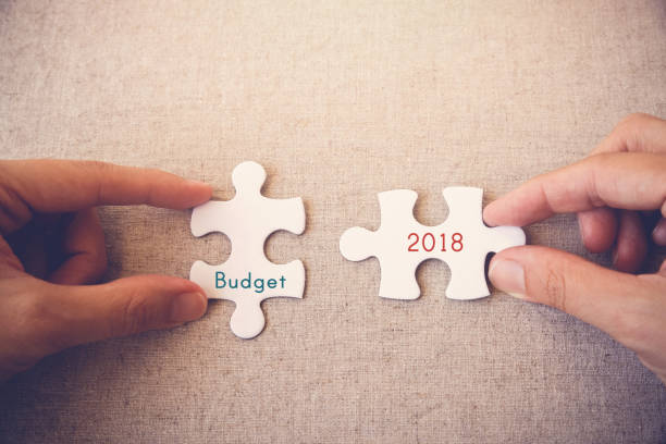 mains avec les pièces du puzzle et mots « budget 2018 » - 2018 photos et images de collection