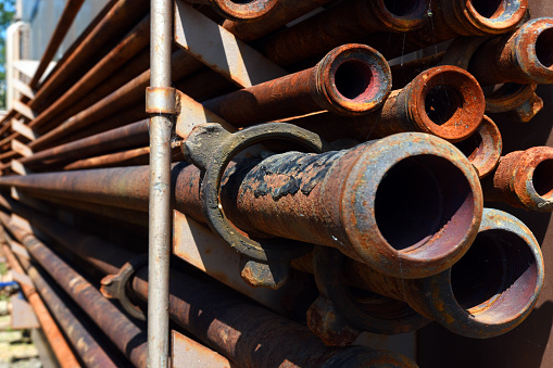 An image of old oilfield ready-rod pipes hung on a rack.