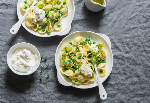 Pasta with green peas, asparagus and fresh ricotta. On a gray background, top view. Healthy delicious food Pasta with green peas, asparagus and fresh ricotta. On a gray background, top view. Healthy delicious food ricotta stock pictures, royalty-free photos & images