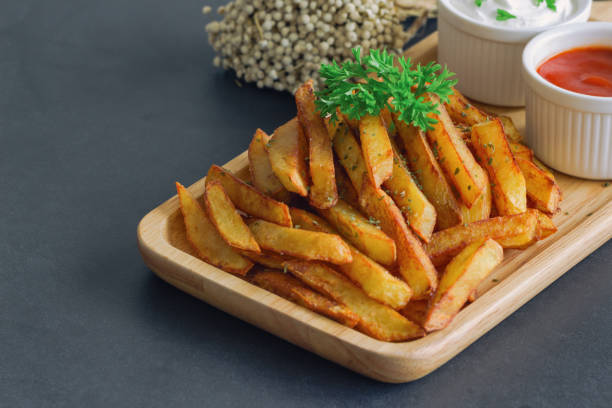 homemade french fries serve with ketchup and sour cream or mayonnaise. golden brown crispy french fries sprinkle salt and oregano on wood plate for snack or appetizer. french fries on granite table. - oregano freshness herb brown imagens e fotografias de stock