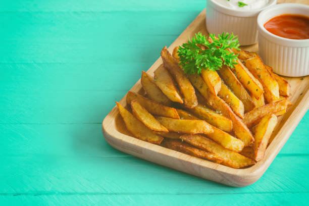 homemade french fries serve with ketchup and sour cream or mayonnaise. golden brown crispy french fries sprinkle with salt and oregano on wood plate for snack or appetizer. french fries on wood table. - oregano freshness herb brown imagens e fotografias de stock