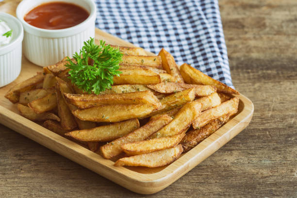 homemade french fries serve with ketchup and sour cream or mayonnaise. golden brown crispy french fries sprinkle with salt and oregano on wood plate for snack or appetizer. french fries on wood table. - oregano freshness herb brown imagens e fotografias de stock