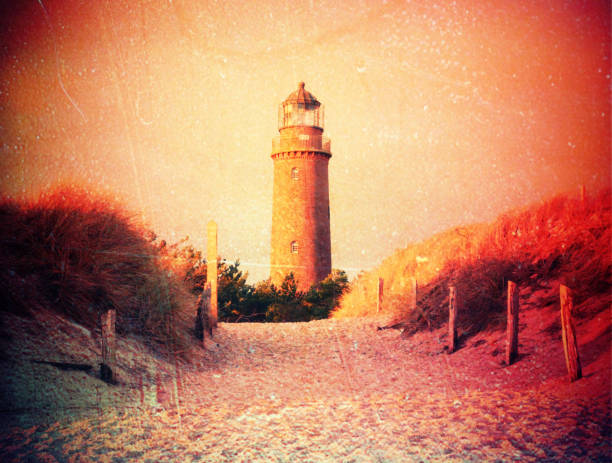 istock Film effect. Historical lighthouse. Shinning lighthouse,  dunes and pine tree. Tower illuminated with strong warning light, 823244768