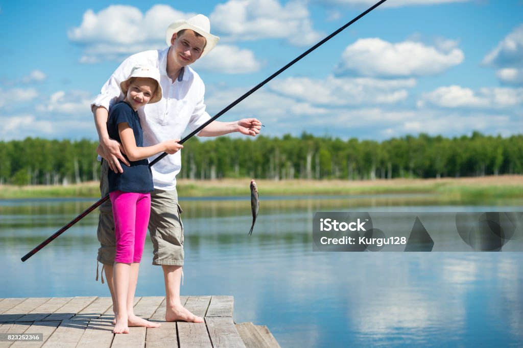 Dad Helps Daughter To Catch Fish With A Fishing Rod On The River