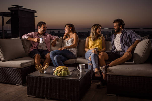 istock Happy couples talking while relaxing on a penthouse balcony at dusk. 823256098