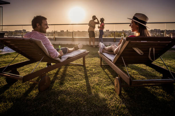 istock Young couple communicating while relaxing on deck chairs at penthouse balcony. 823263496