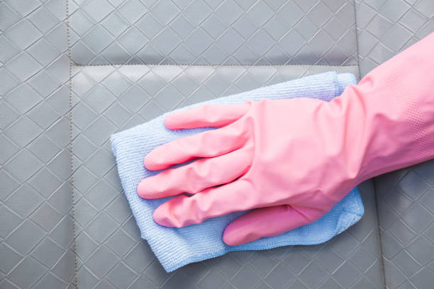 istock Hand in rubber protective glove with microfiber cloth cleaning a minibus interior's leather seat. Early spring professionally chemical cleaning or regular clean up. 823270082