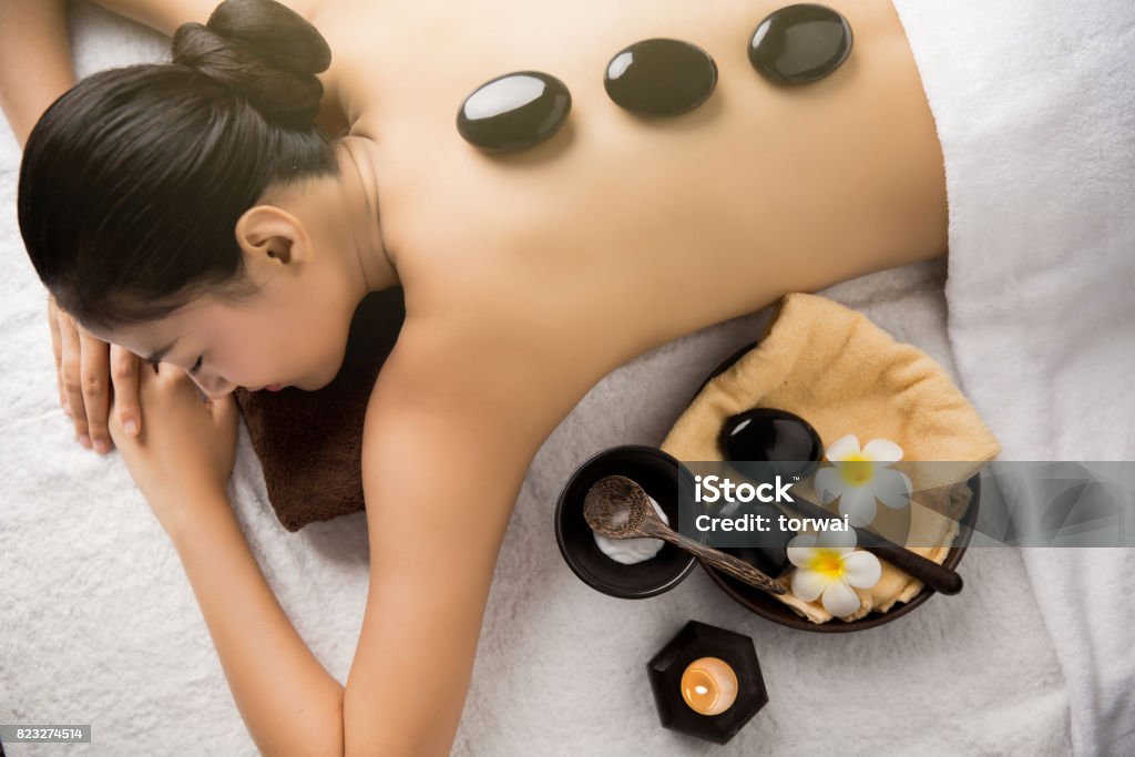 Asian woman having massage and spa salon Beauty treatment concept. She is very happy Spa stone massage. beauty treatments. spa hot stones.top view Adult Stock Photo