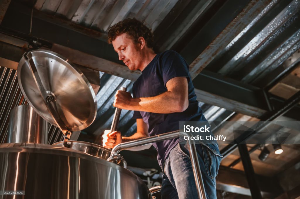 Man Brewing Beer A man is brewing and checking the craft beer. Brewery Stock Photo