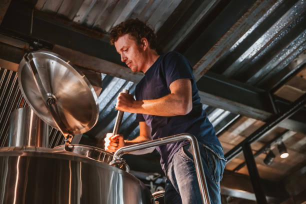 Man Brewing Beer A man is brewing and checking the craft beer. artisanal food and drink photos stock pictures, royalty-free photos & images