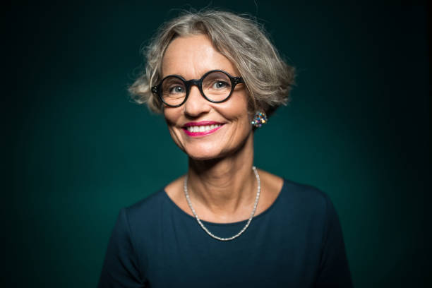 Happy Woman In Eyeglasses Against Green Background Portrait of cheerful woman in eyeglasses against green background. Smiling female is wearing jewelry. She is having short gray hair. middle aged woman fashion stock pictures, royalty-free photos & images
