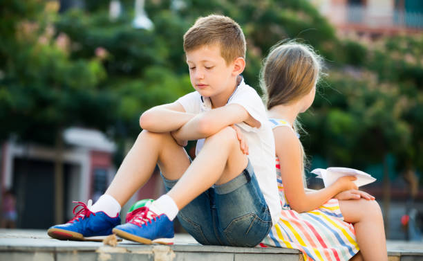 istock Portrait of sad boy sitting in park 823311498