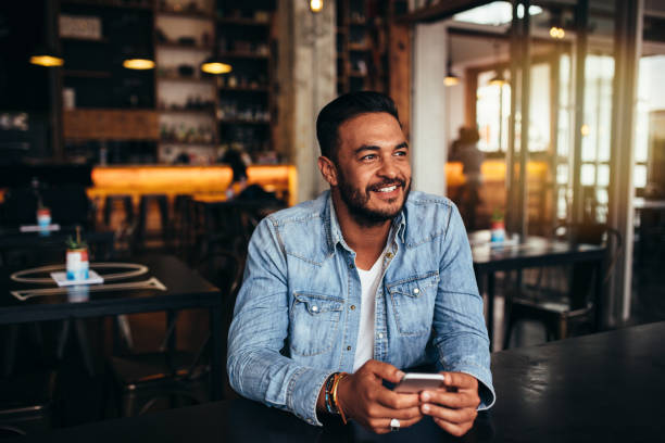 istock Young man sitting in coffee shop with mobile phone 823315906