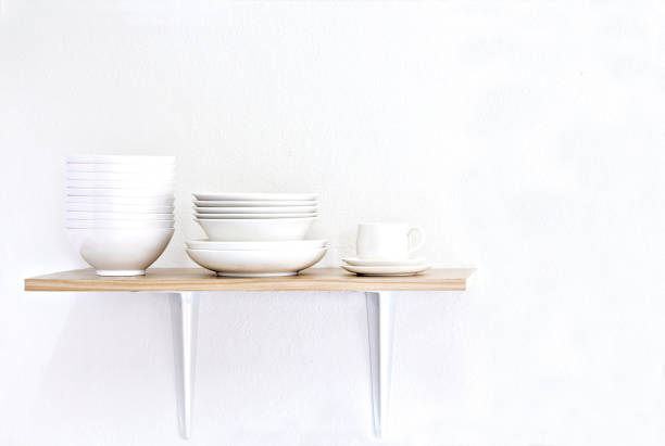 Stack of white bowls, plate and cup on wooden table and white background.