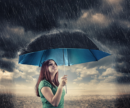 Young girl holding an umbrella in the rain, sunny under umbrella.