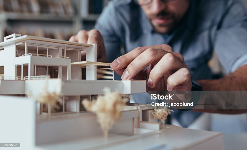 Male architect hands making model house Close up of male architect hands making model house. Man architect working in the office. Architect Stock Photo